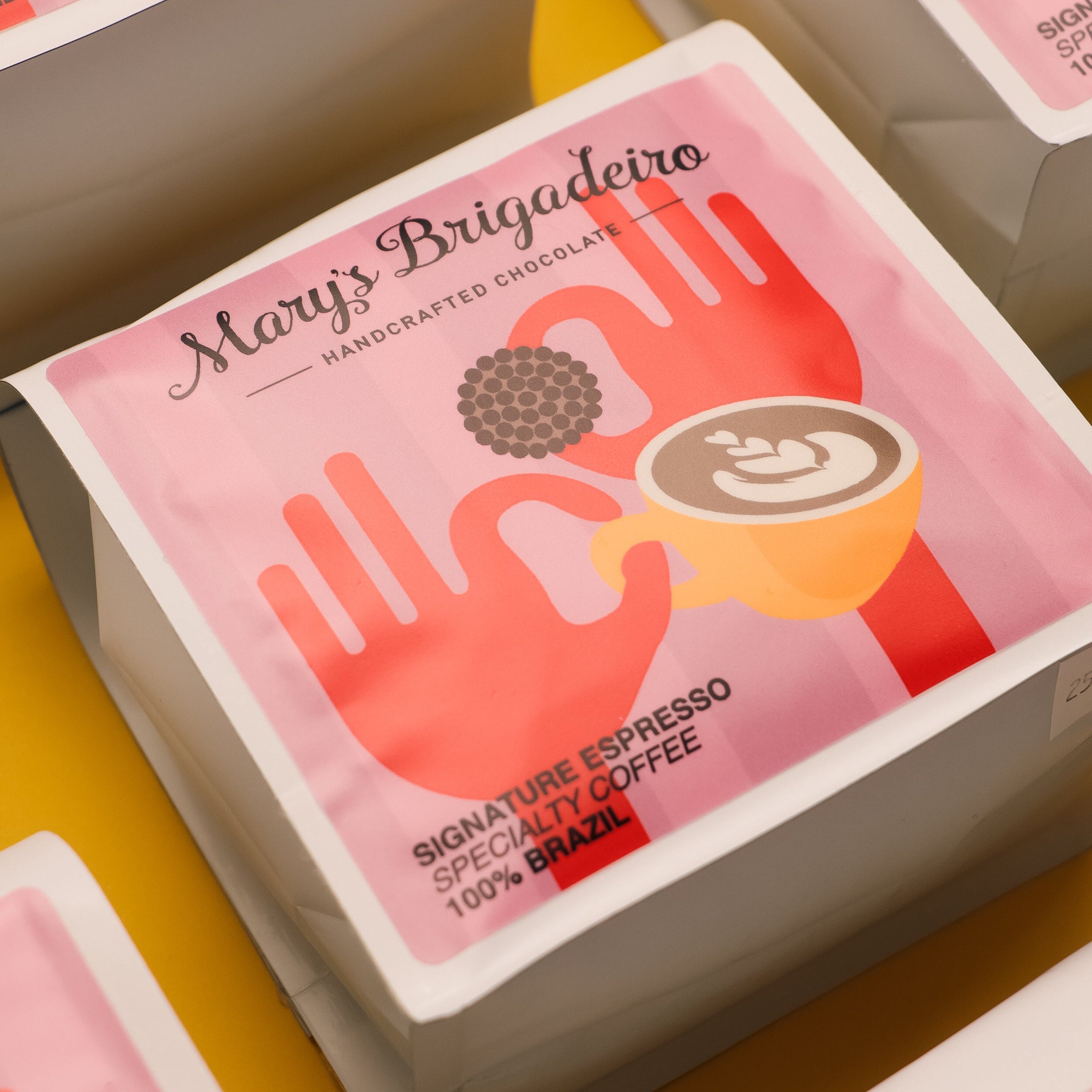 Mary's Brigadeiro coffee packaging with a red hand holding a coffee cup design on a yellow background.