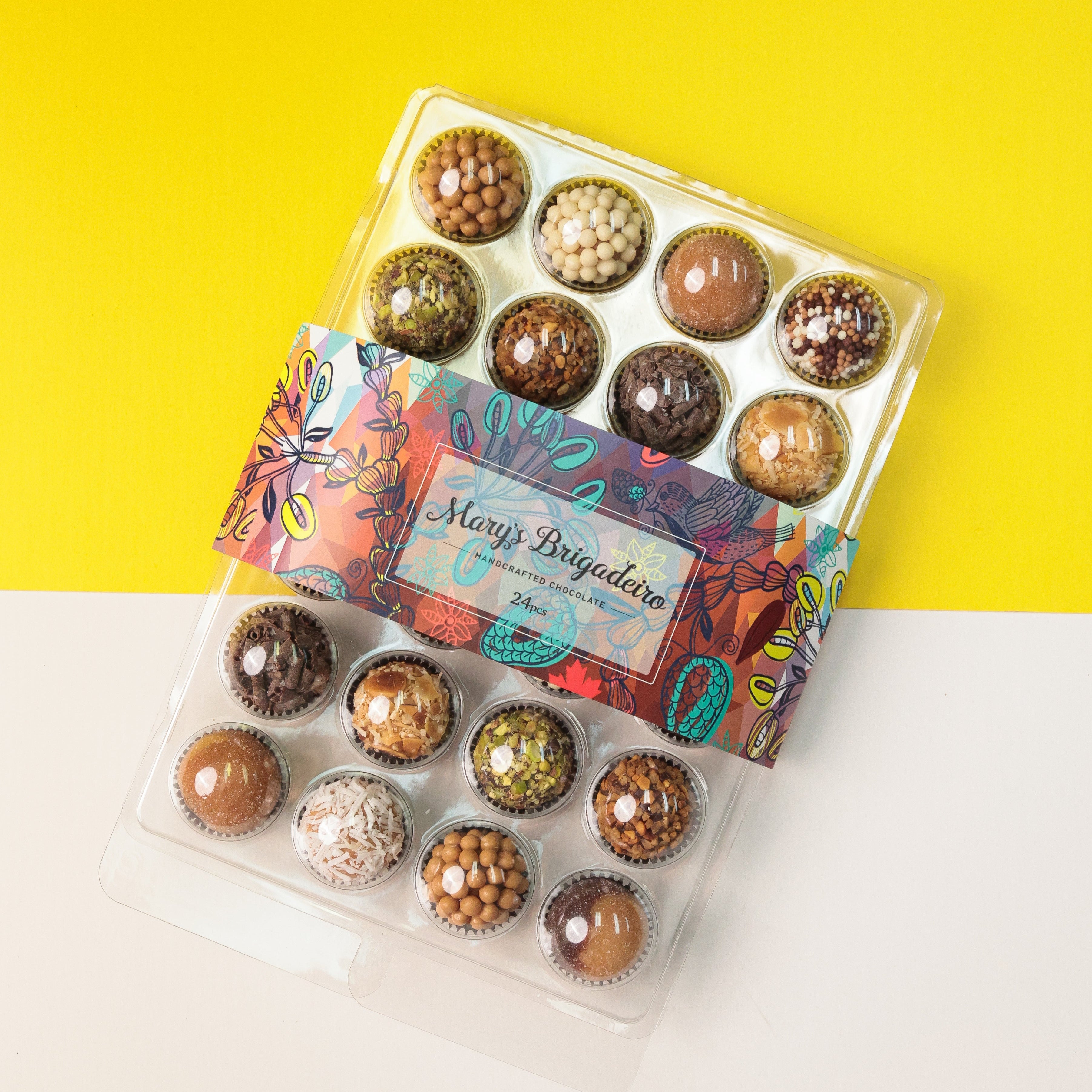 A clear plastic party tray filled with assorted chocolate covered candies, presented on a colorful background.