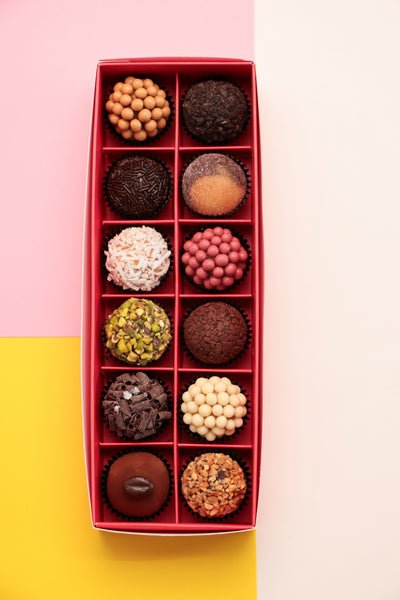 Box of assorted 12 pieces Brigadeiro chocolates with a decorative box on a colorful background