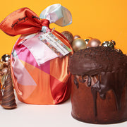 Decorative gift bag with a colorful bow and a chocolate cake on an orange background